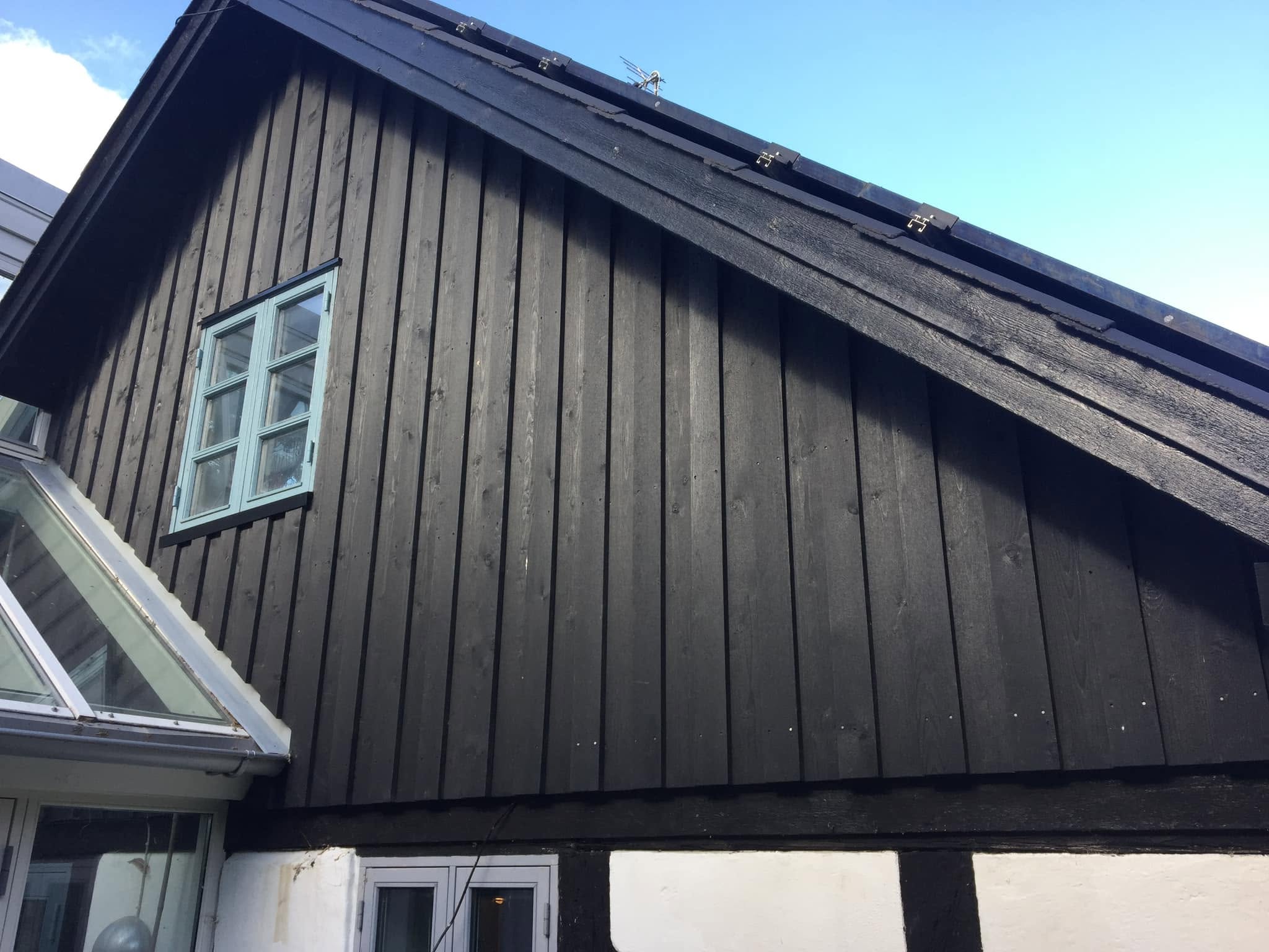 Færdig sort lodret gavlbeklædning i træ på hus med bindingsværk